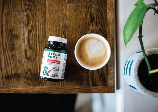 Stem and Root Brain Boost on a wooden coffee table next to a mug of coffee